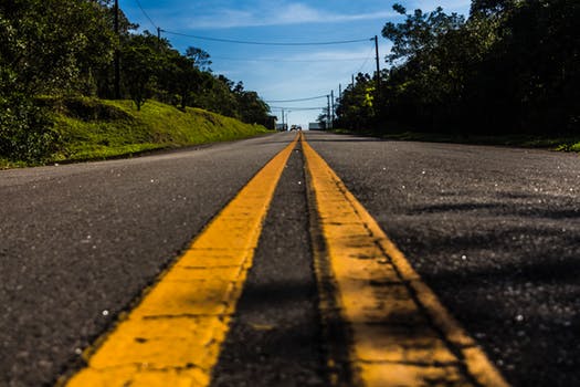 Similar to tarmac driveways a long stretch of tarmac road with yellow lines.